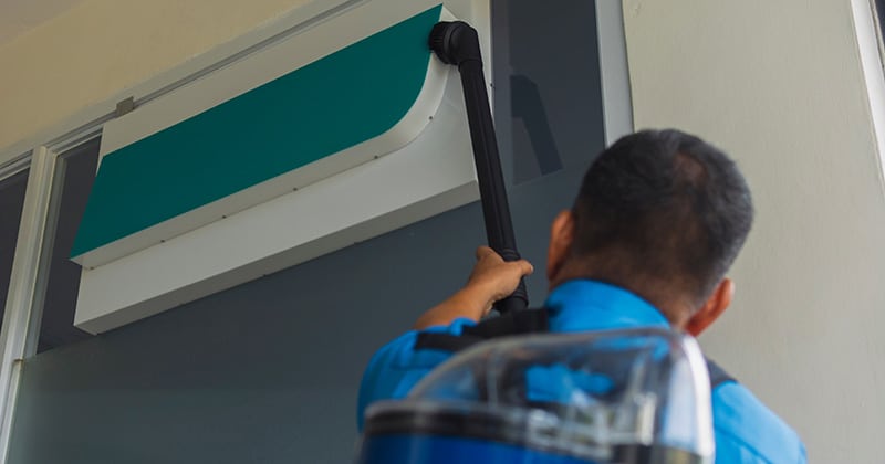 Cleaning pro using backpack vacuum cleaner to clean signage in office
