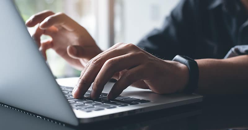 Hands typing on laptop