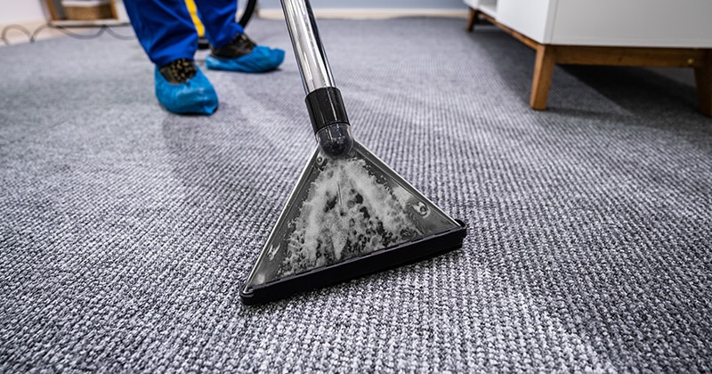 Man wearing boot covers, cleaning carpet